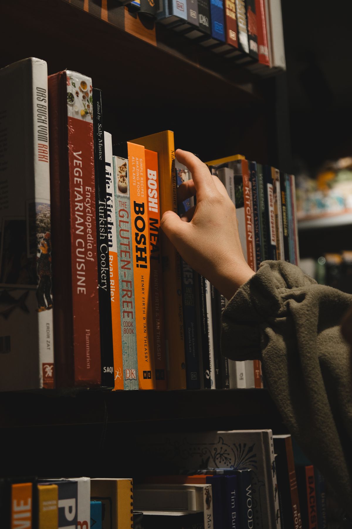 A reader pulling a book from a bookstore shelf
